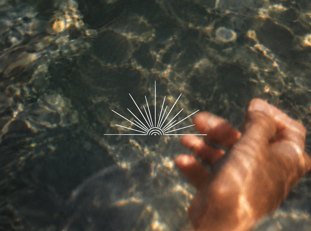 Una mano rozando el agua iluminada por el sol